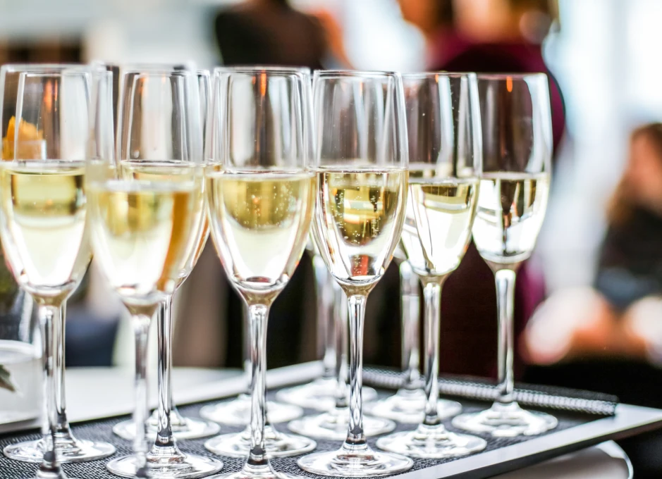 Vasos de champán sobre una bandeja, con un fondo borroso de personas.