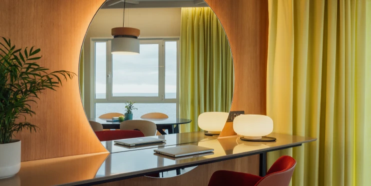 Escritorio con espejo grande, lámpara redonda y cortinas amarillas en un espacio moderno.