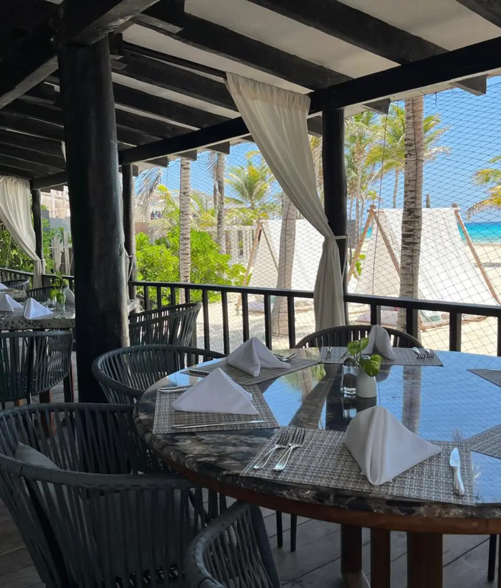 Comedor al aire libre con vista a la playa y mesas bien preparadas.