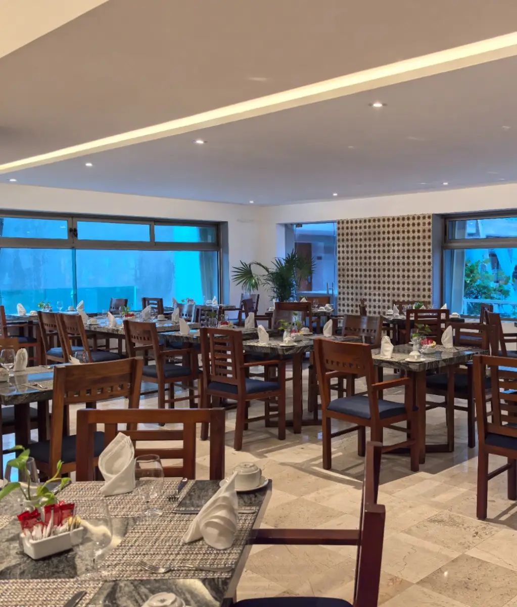 Restaurante elegante con mesas de madera y manteles listos para los comensales.