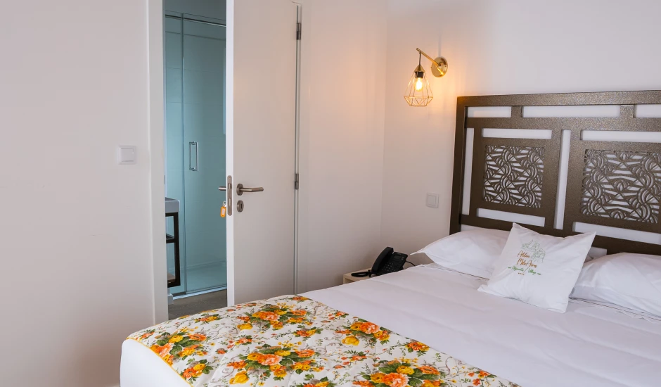 Quarto de hotel aconchegante com cama de solteiro e decoração floral.