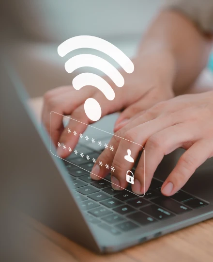 Pessoa digitando no laptop com ícone de Wi-Fi e senha digital no ar.