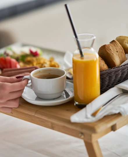 Café da manhã na cama com suco, café, pães e pratos variados.