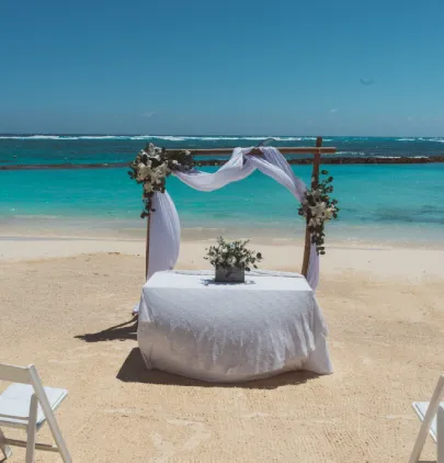 Altar de boda decorado en una playa de arena blanca con el mar turquesa de fondo.
