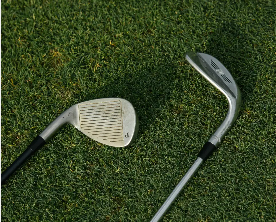 Dos palos de golf sobre césped, uno con la cara visible.