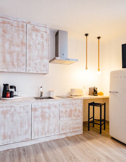 Cozinha compacta branca, com eletrodomésticos e iluminação pendente.