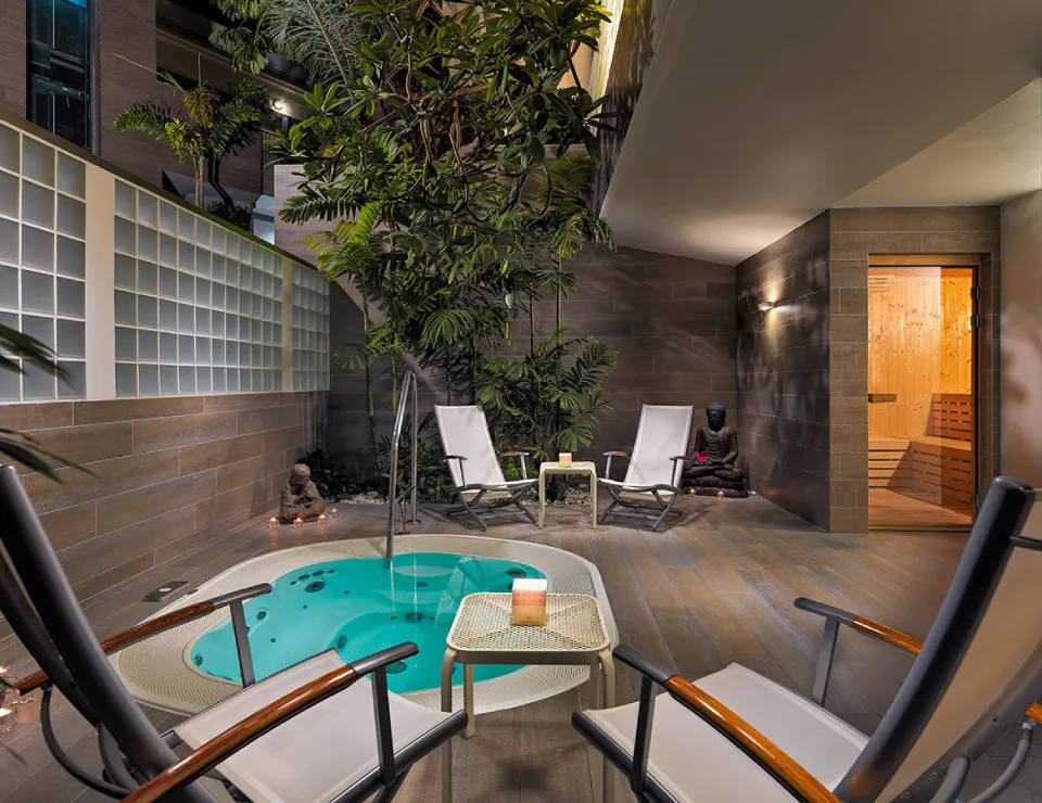 Patio con jacuzzi, plantas, tumbonas y sauna. Ambiente relajante y moderno.