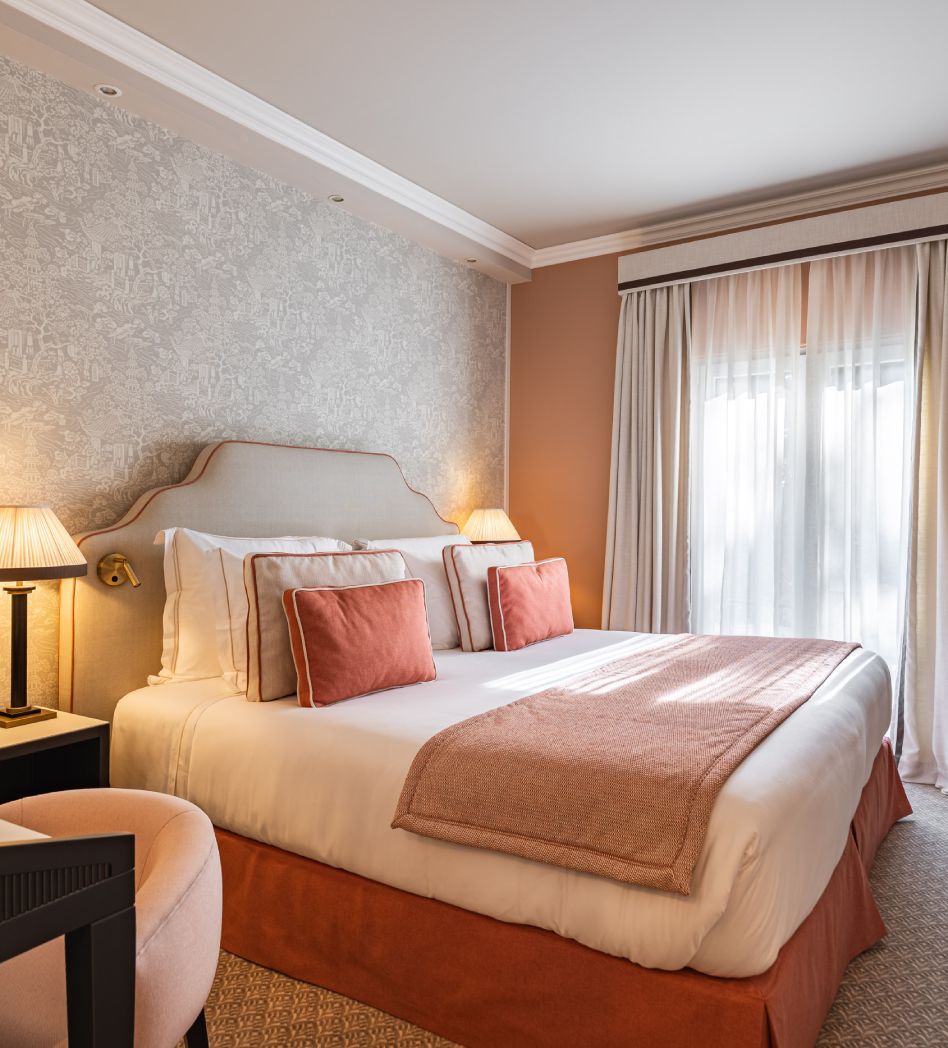 Cozy bedroom with pink and beige decor, featuring a double bed and soft lighting.