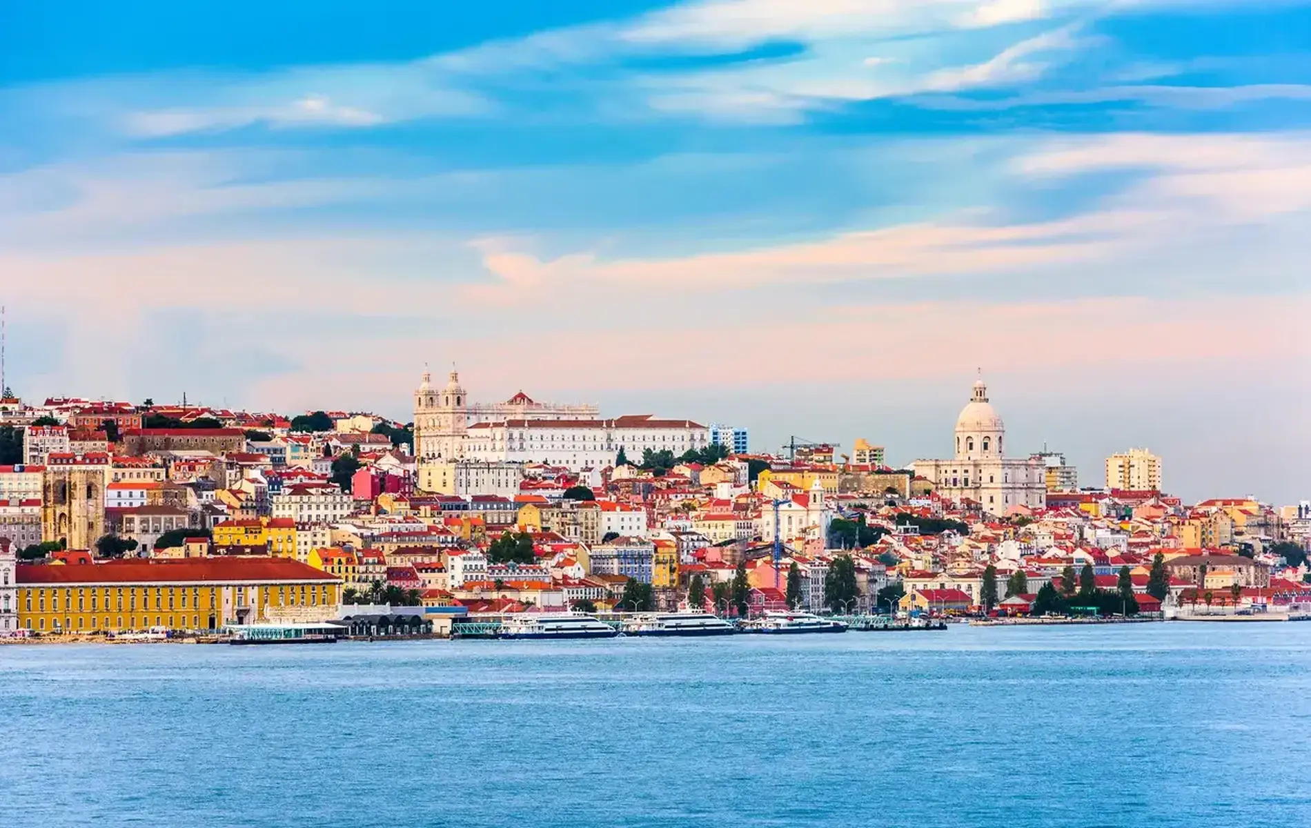 Sunny cityscape with colorful buildings and waterfront under a blue sky.