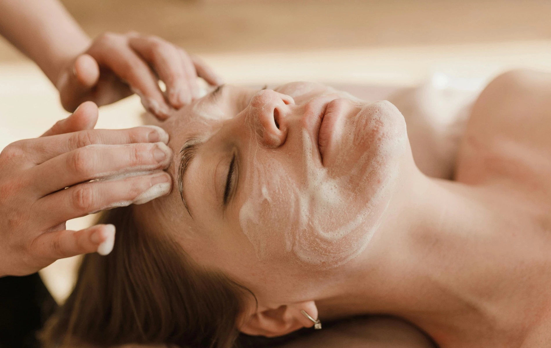 Person receiving a relaxing facial massage with a creamy cleanser.