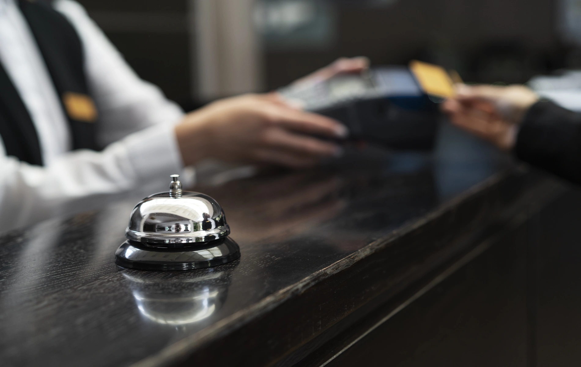 A hotel bell on a counter with a card transaction happening in the background.