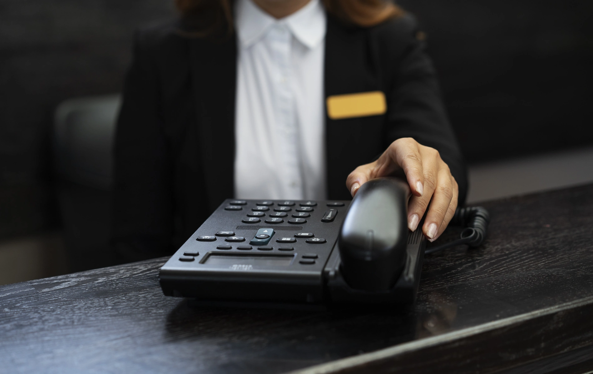 Person answering a desk phone in an office setting.