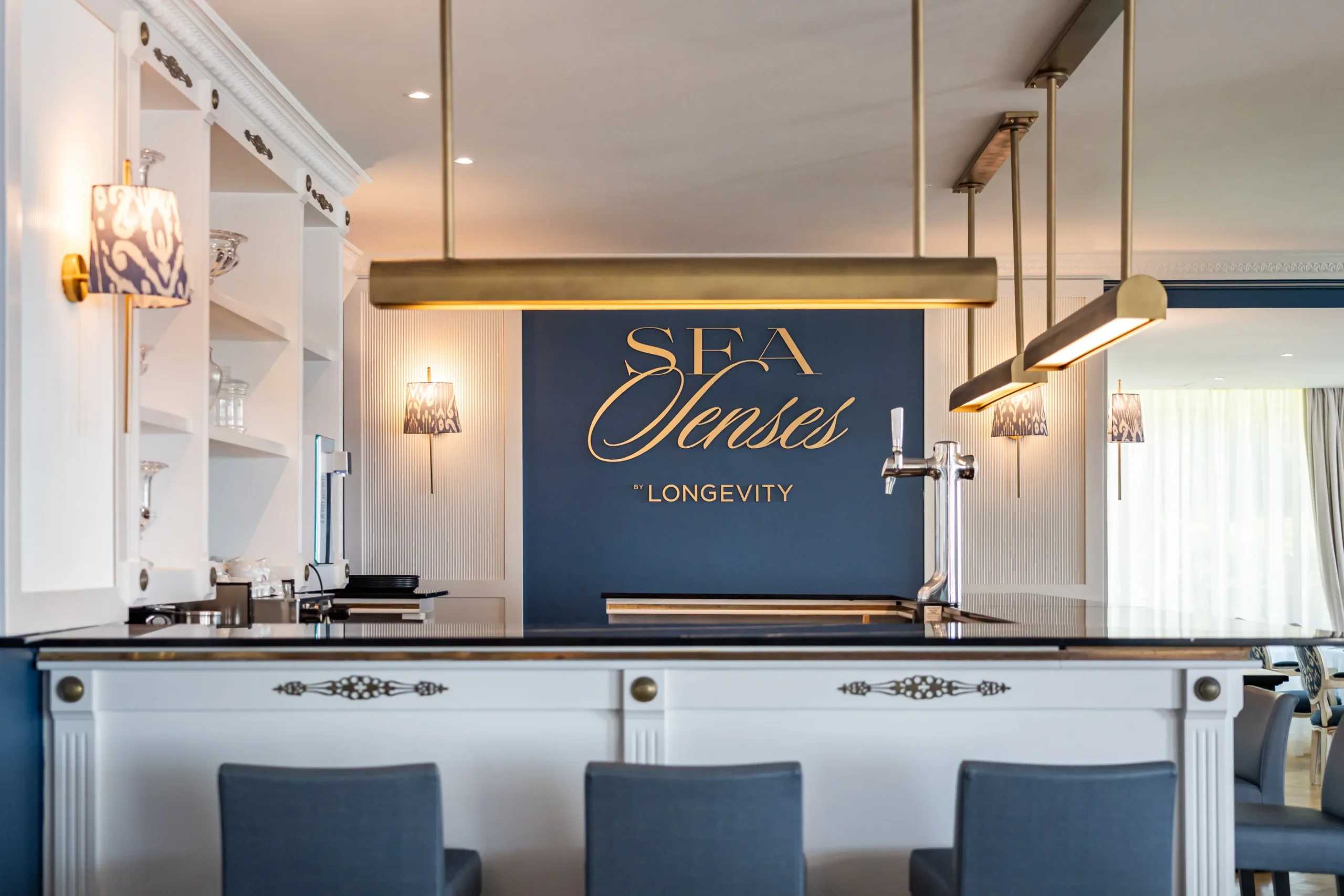 Elegant bar interior with a navy and gold theme, featuring "Sea Senses" by Longevity signage.
