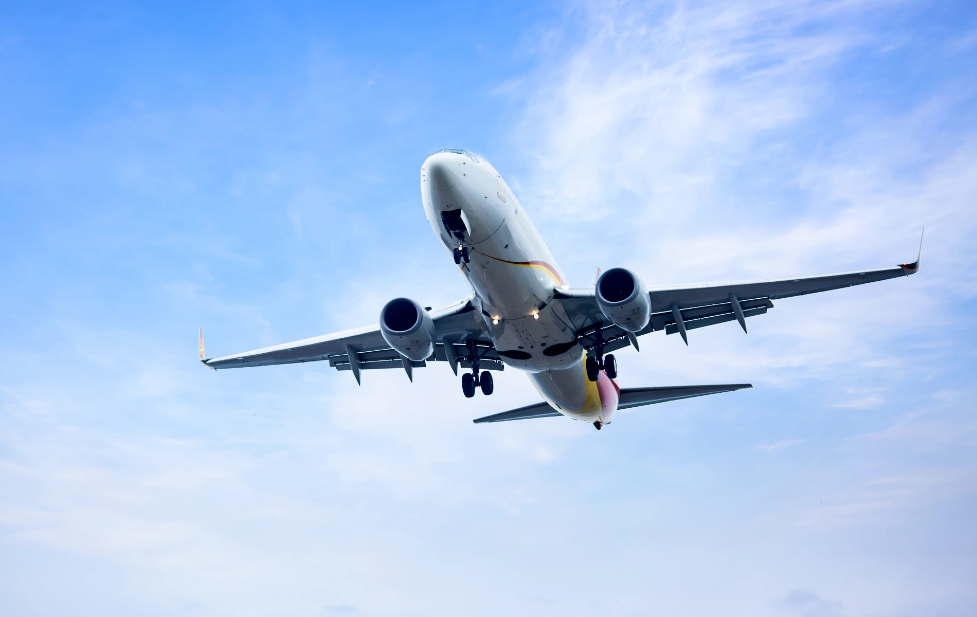 Airplane flying against a blue sky with visible landing gear.