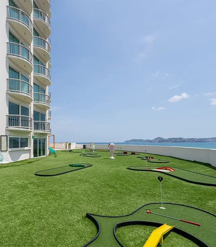 Mini golf en la azotea de un edificio junto al mar, con un cielo despejado.