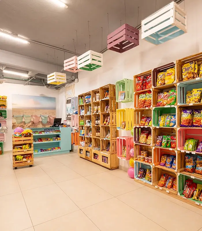 Una tienda con estantes de cajas de madera y bolsitas de papas y snacks.