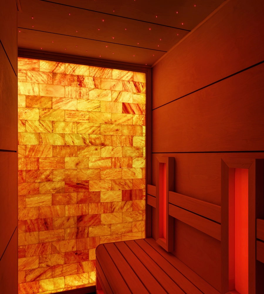 Sauna con paredes de sal iluminadas, bancos de madera y un techo decorado con peque&ntilde;as luces rojas.