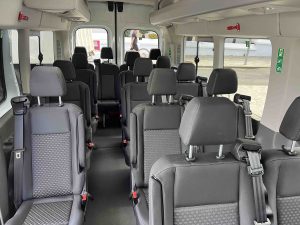 Interior de una camioneta con asientos vac&iacute;os y ventanas laterales grandes.