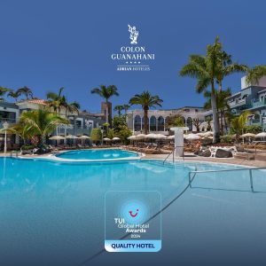 Piscina de hotel con palmeras, edificio colonial y logo de premios TUI 2024 como "Quality Hotel".