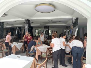 Grupo de personas reunidas en un restaurante luminoso con mesas vestidas y sillas de madera.