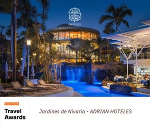 Hotel iluminado por la noche con piscina y cascada. Texto: "Jardines de Nivaria - ADRIAN HOTELES".