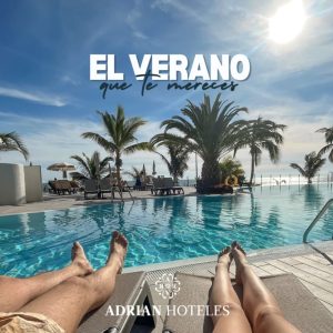 Una piscina con palmeras, cielo azul y texto "El verano que te mereces - Adrian Hoteles".