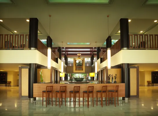 Vestíbulo moderno con barra de madera, sillas, lámparas colgantes y decoración elegante.