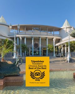 Hotel con premio "Tripadvisor Travelers' Choice 2025". Fachada moderna, fuente al frente.