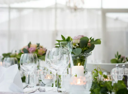 Mesa elegante con copas, flores y velas en un evento.