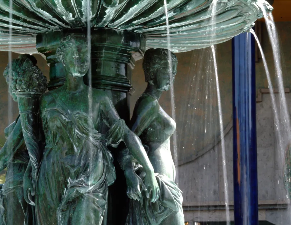 Escultura de figuras femeninas en una fuente con agua cayendo sobre ellas.