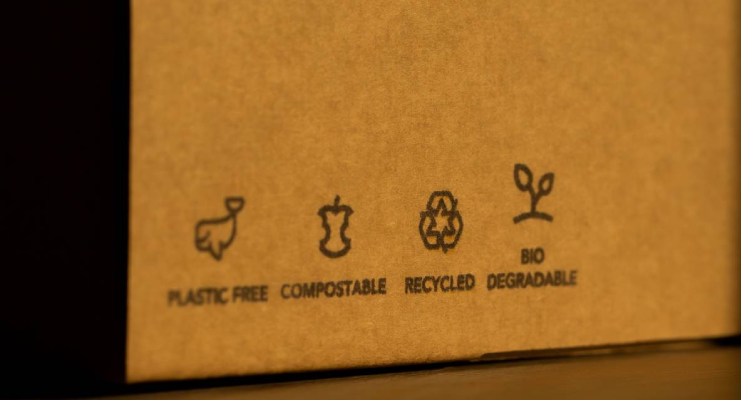 Iconos en una caja marrón indicando: plástico libre, compostable, reciclado, biodegradable.