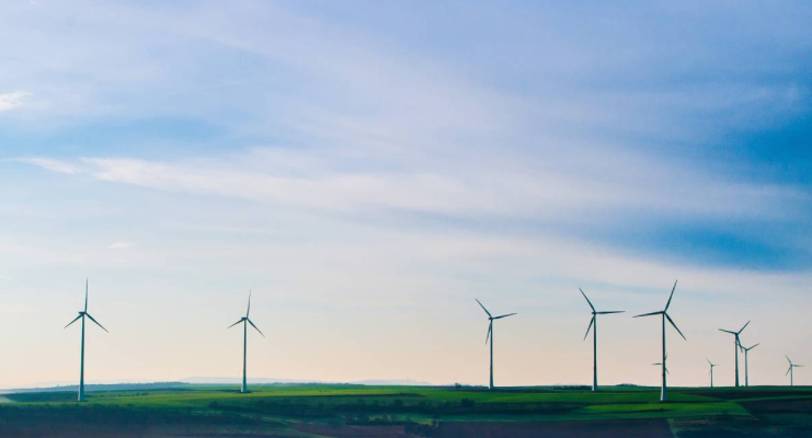 Campo con varios aerogeneradores bajo un cielo azul claro.