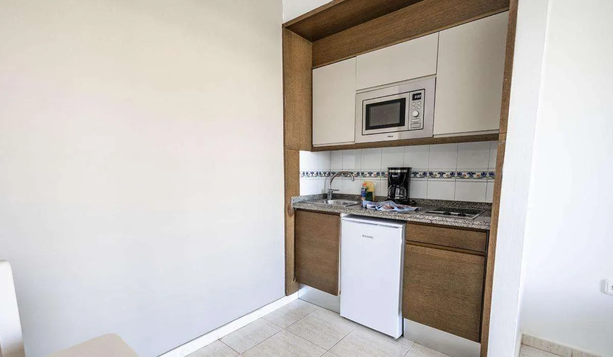 Cocina pequeña con microondas, fregadero, cafetera y mini nevera.