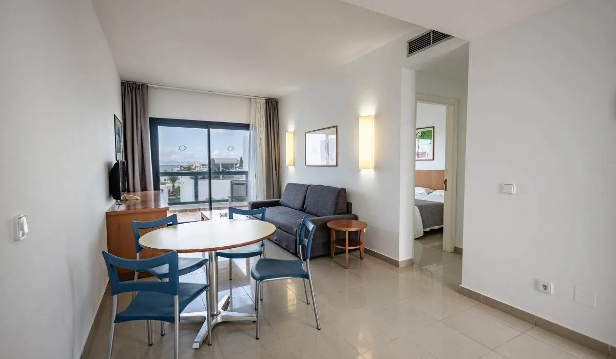 Sala de estar moderna con sofá, mesa y vista al balcón.