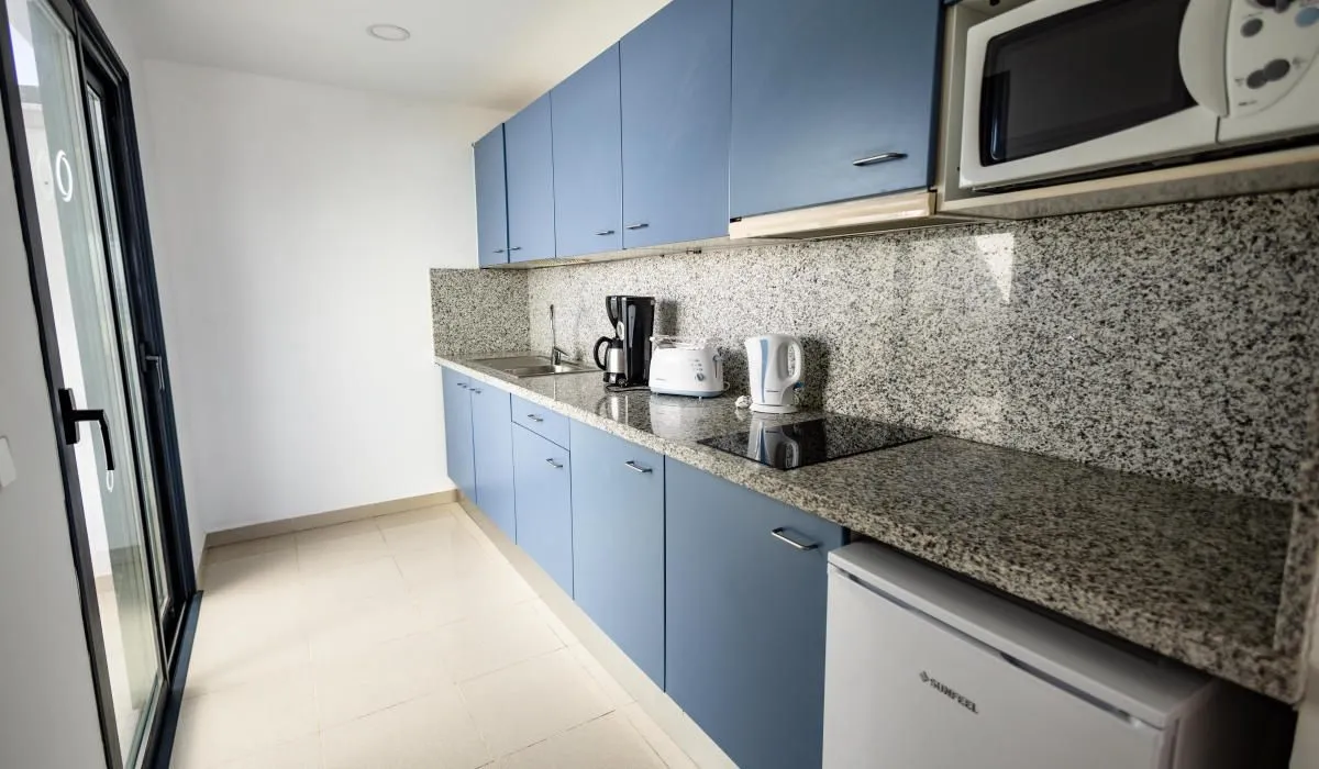 Cocina moderna con gabinetes azules y electrodomésticos sobre encimera de granito.