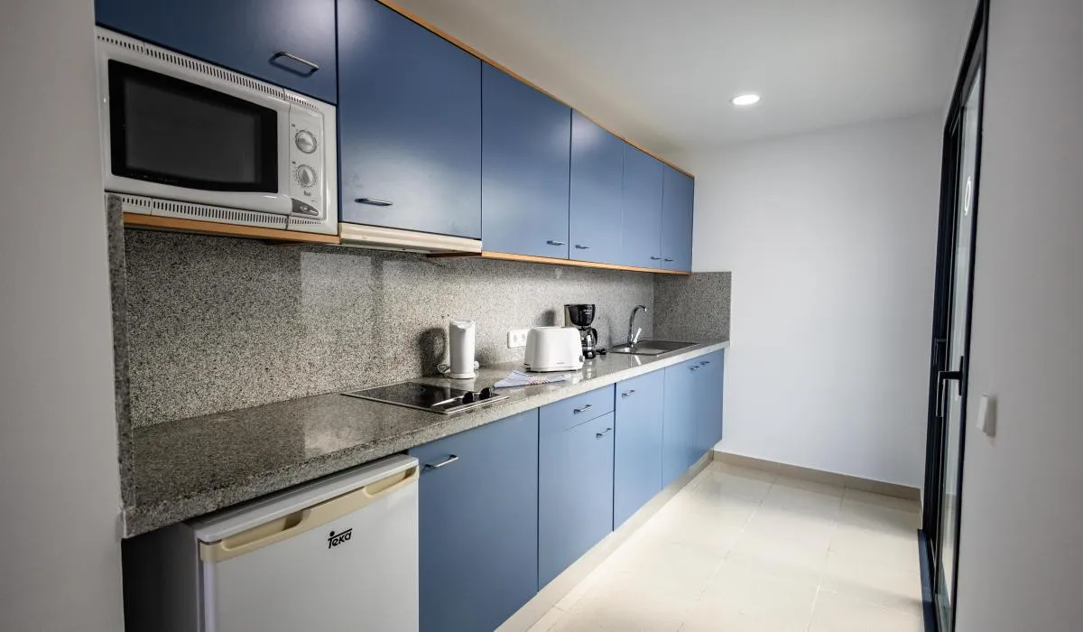 Cocina moderna con gabinetes azulados y electrodomésticos variados.