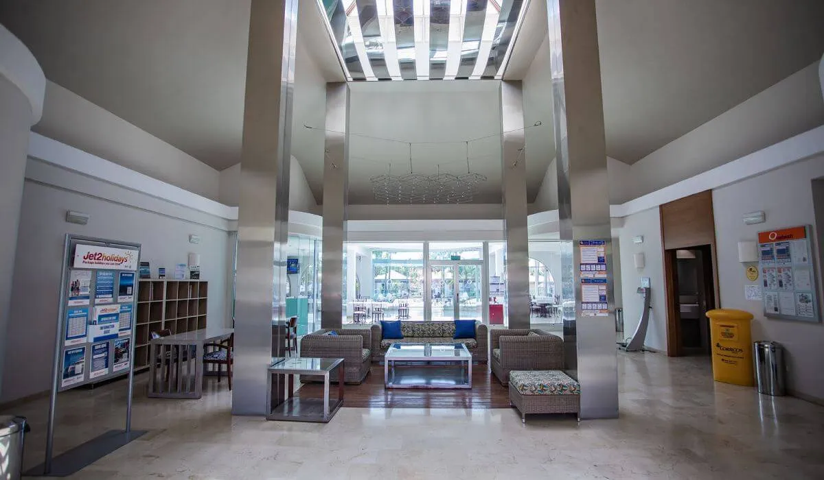 Vestíbulo moderno con sofás y techo alto iluminado.