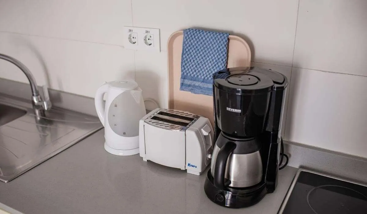 Cafetera, tetera y tostadora en una encimera de cocina.