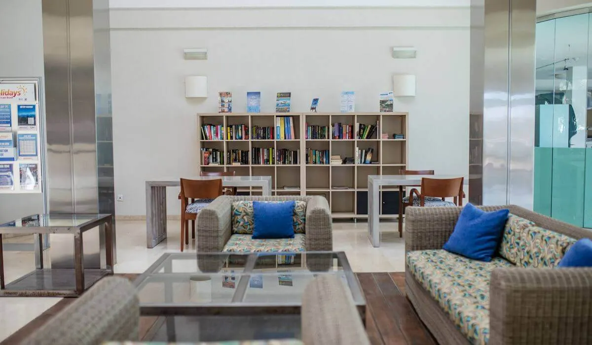 Sala de estar con sofás, estantería y mesas; ambiente moderno y acogedor.