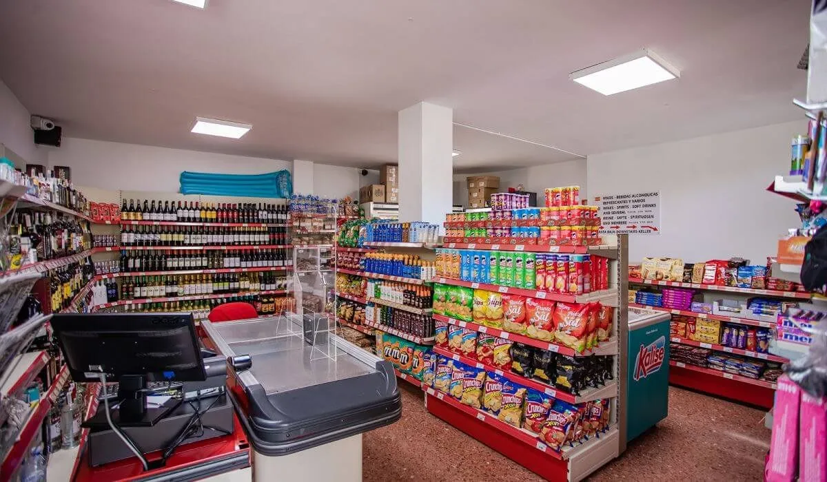 Tienda de abarrotes con estantes llenos de botellas y productos diversos.
