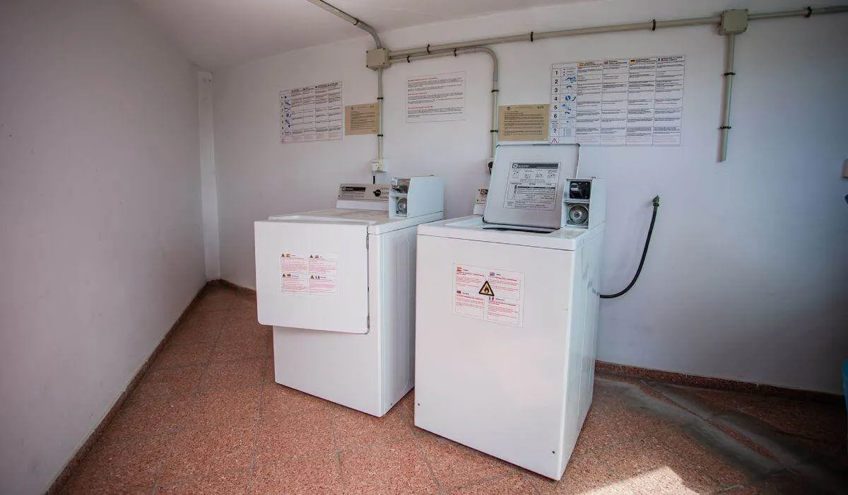 Lavandería con dos máquinas blancas y paredes con instrucciones.