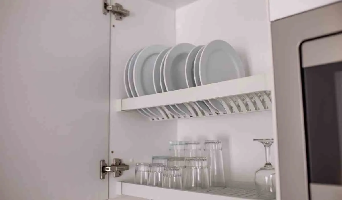 Platos y vasos ordenados en un gabinete de cocina blanco.