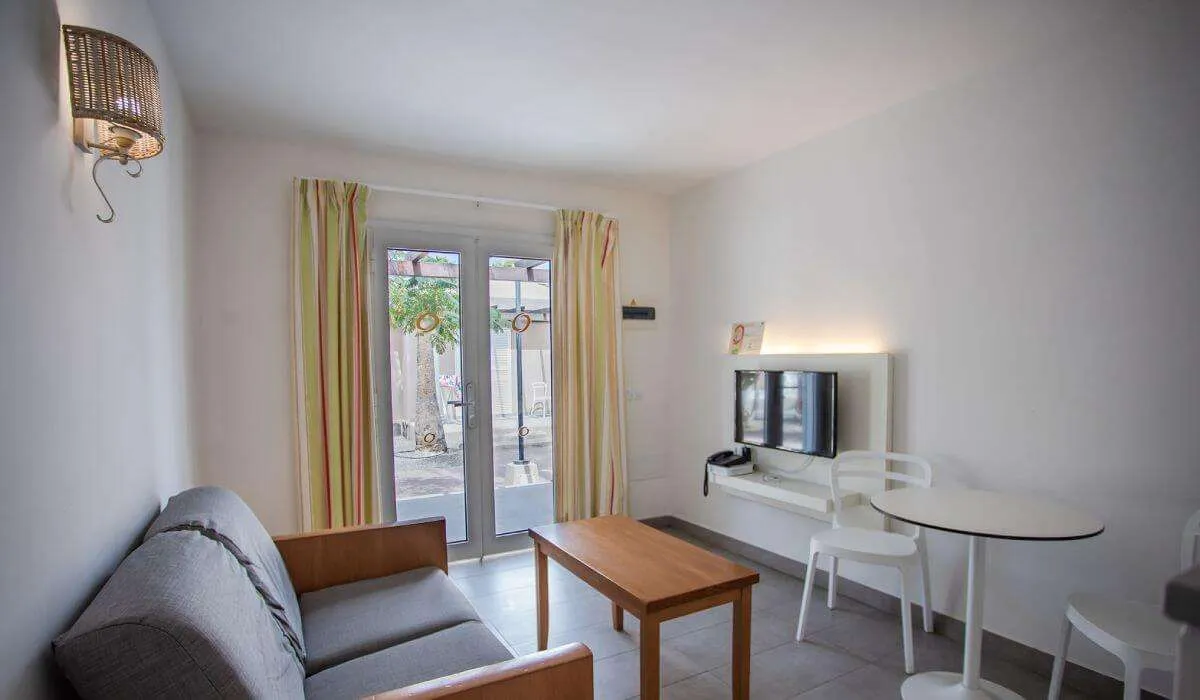 Sala moderna y minimalista con sofá, mesa y televisor en la pared.