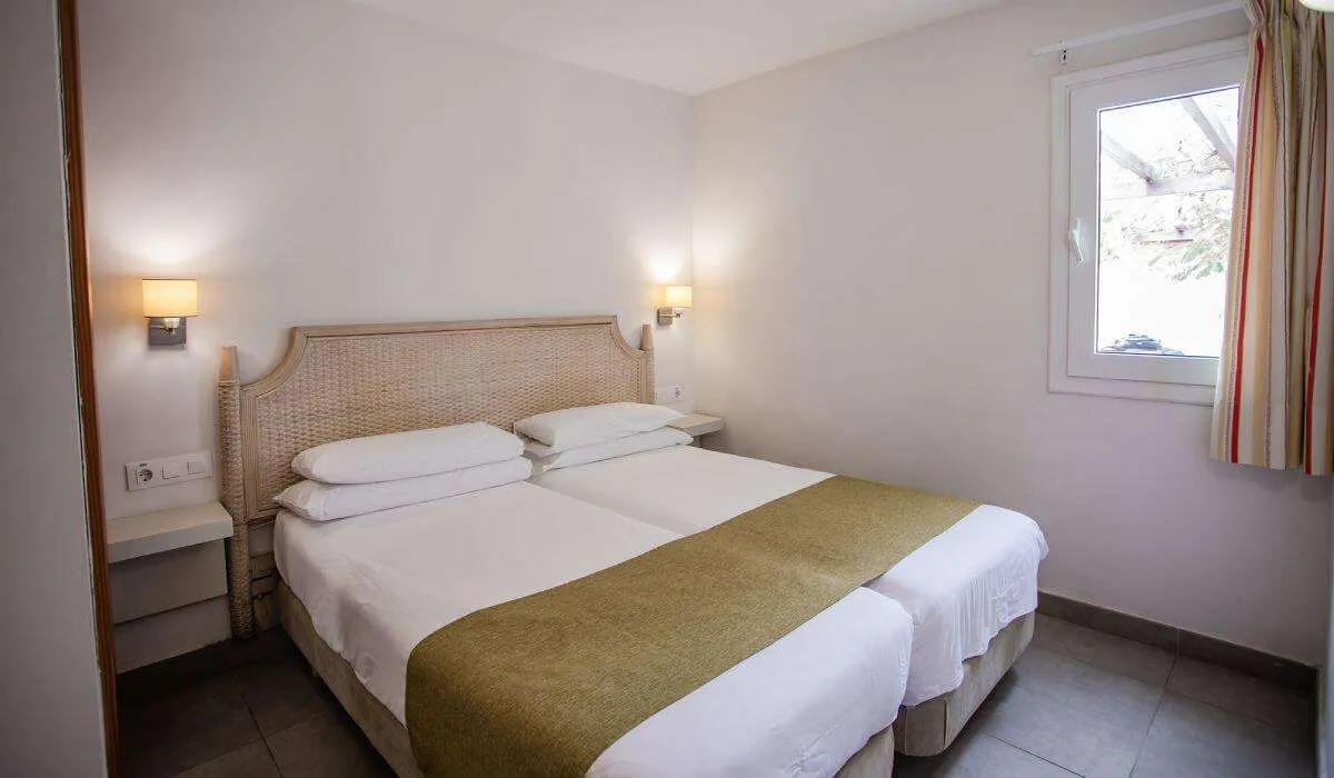 Habitación con dos camas individuales y luz tenue, ventana a la derecha.