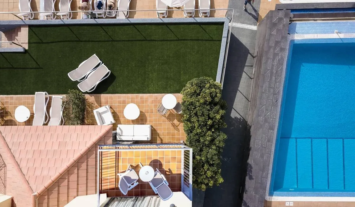 Vista aérea de una terraza con tumbonas, mesas y piscina junto.
