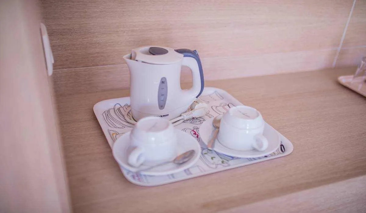 Tetera eléctrica y tazas sobre una bandeja en una encimera de madera.