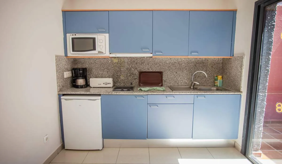 Cocina pequeña con electrodomésticos y muebles azules.