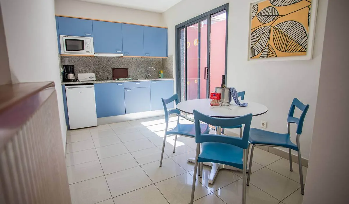 Cocina moderna con muebles azules y mesa redonda con sillas.