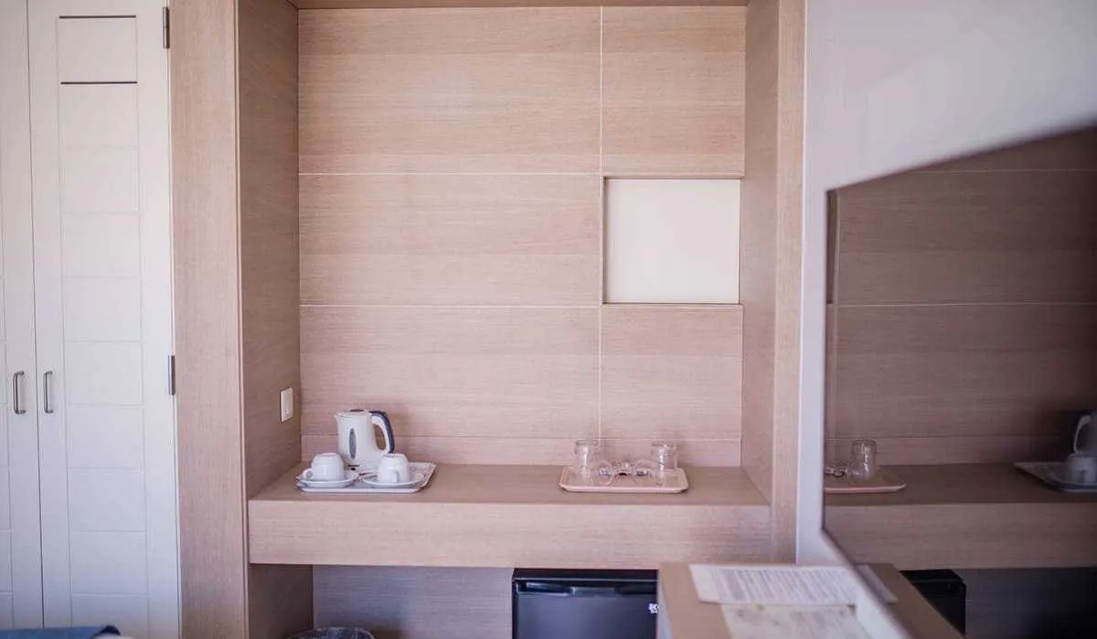 Habitación de hotel con bandeja de tazas y hervidor sobre el escritorio.