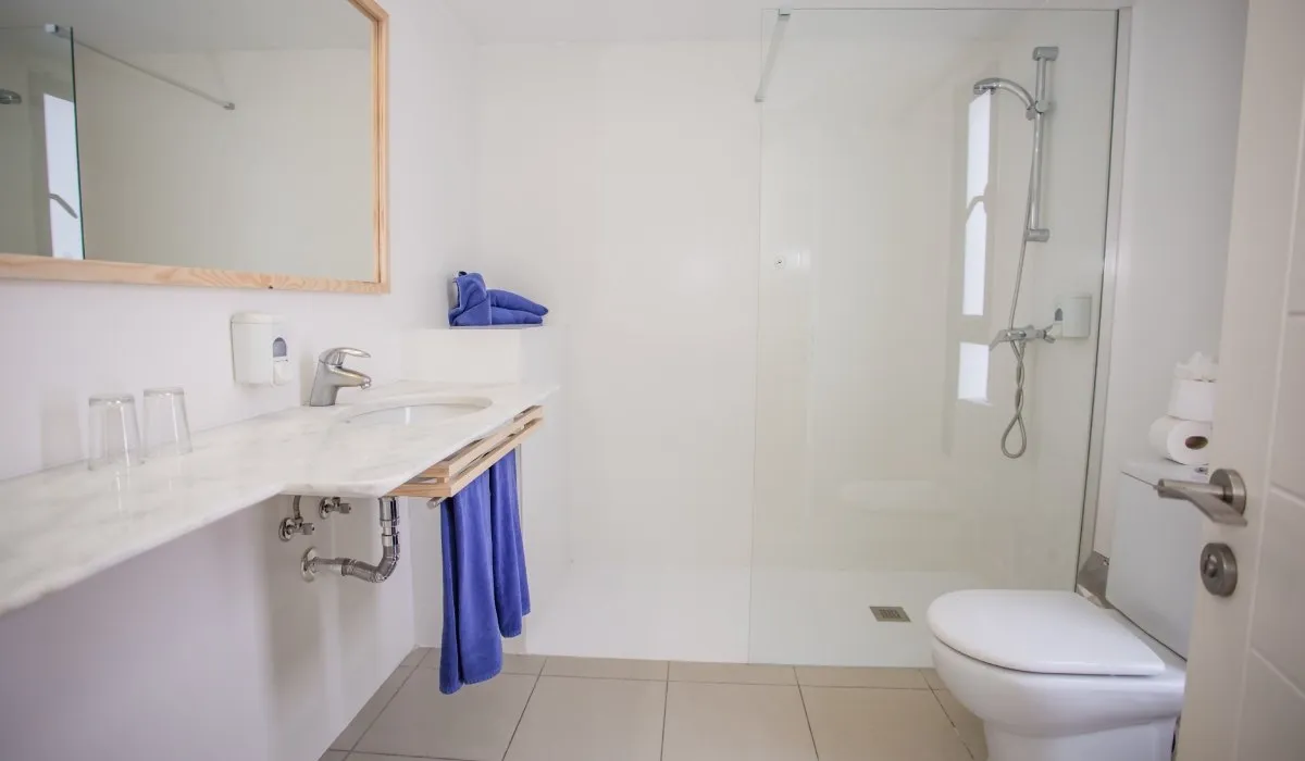 Baño moderno con ducha, lavabo y toallas azules.